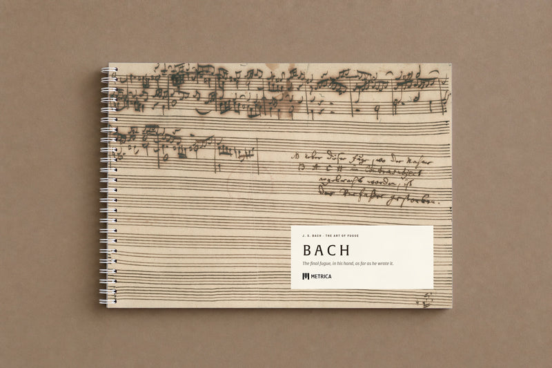 B A C H — the notebook closed: the last page of the fugue on the cover, where the music stops and the note begins, white spiral on the left, digitally composed product view