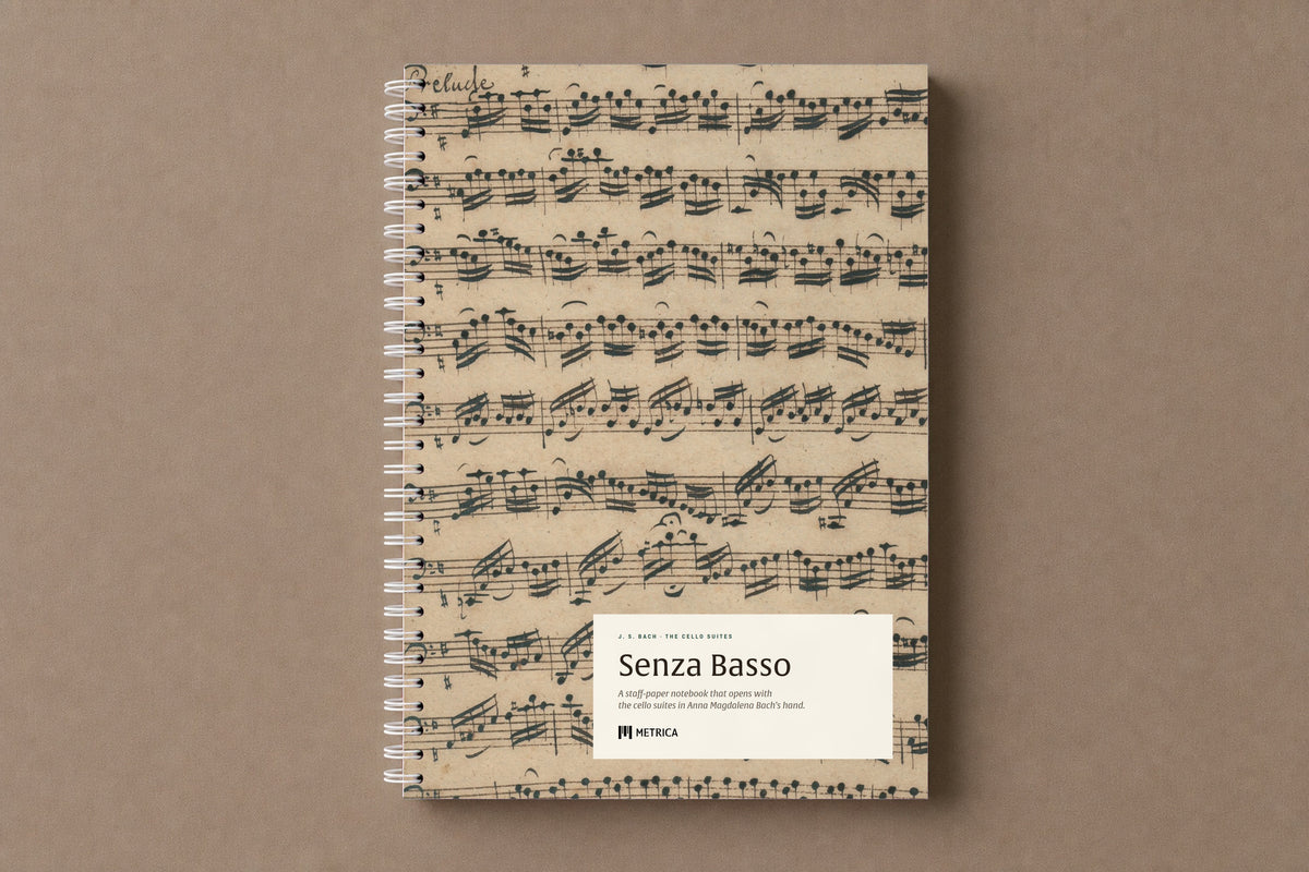 Senza Basso — the notebook closed: the Prelude of the first suite in Anna Magdalena Bach's hand on the cover, white spiral on the left, digitally composed product view