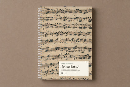 Senza Basso — the notebook closed: the Prelude of the first suite in Anna Magdalena Bach's hand on the cover, white spiral on the left, digitally composed product view
