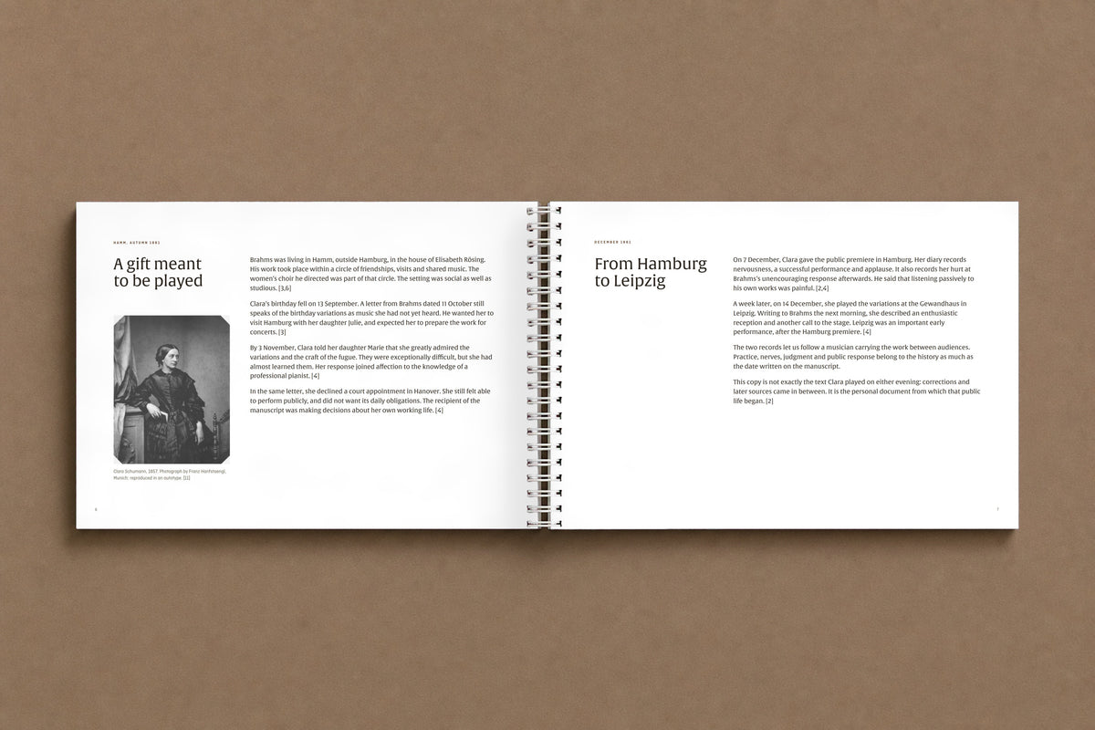 Brahms — Handel Variations, Op. 24 — open notebook at the pages on Clara Schumann and the premiere, with her 1857 portrait, digitally composed product view