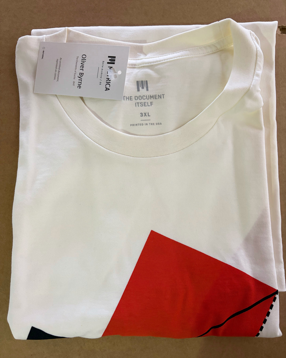 Oliver Byrne T-shirt, photographed at fulfillment: folded natural cotton, printed neck label and Serie Archivo hang tag.